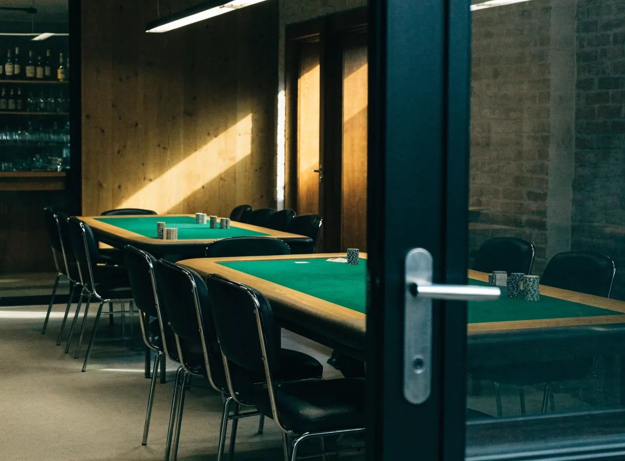 Wnętrze wydzielonej sali z dwoma stołami pokerowymi widziane od strony drzwi
